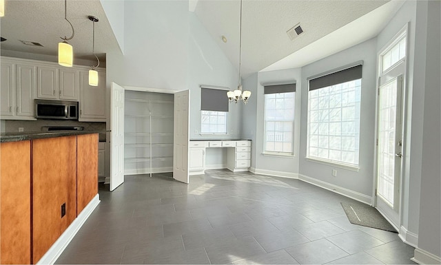 kitchen with an inviting chandelier, decorative light fixtures, high vaulted ceiling, and a textured ceiling