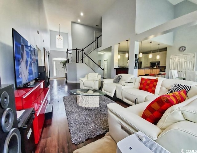 living room with a towering ceiling, wood finished floors, recessed lighting, baseboards, and stairs