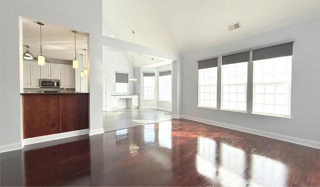 unfurnished living room with dark wood finished floors, visible vents, and baseboards