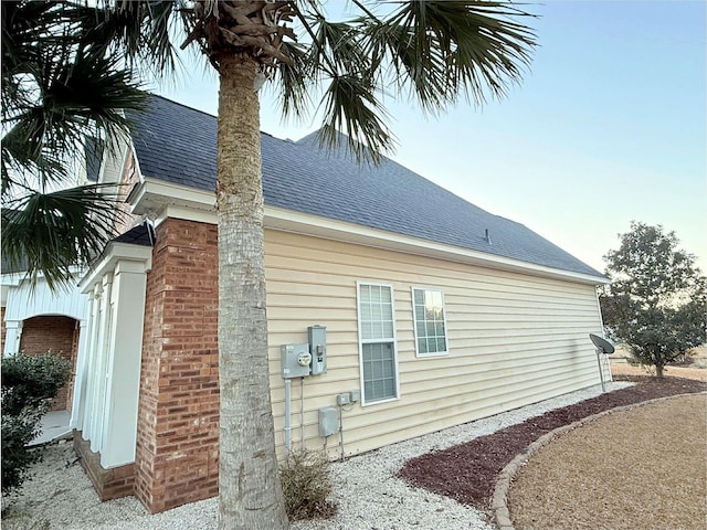 view of side of home with roof with shingles