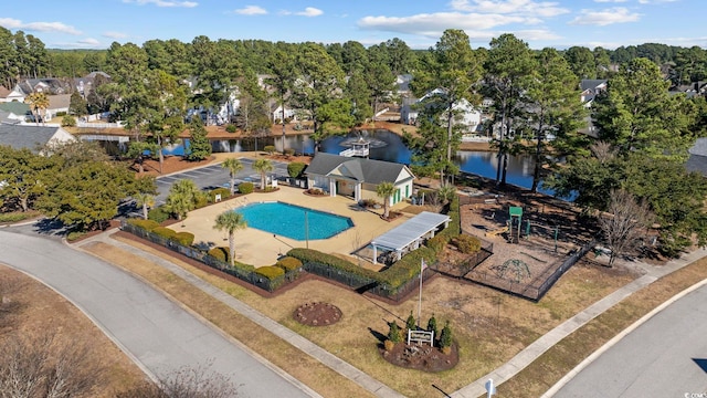community pool with fence, a patio, and a water view