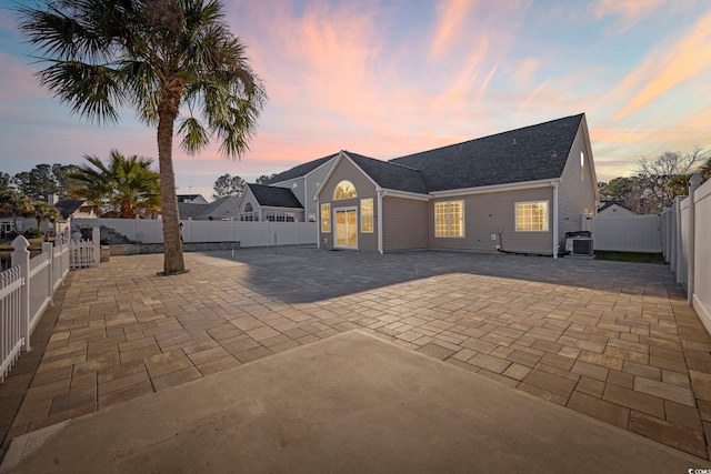 back house at dusk featuring cooling unit and a patio area