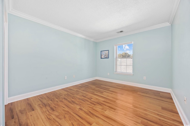 empty room featuring ornamental molding, a textured ceiling, and light wood-type flooring