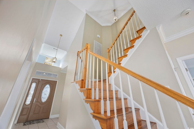 tiled entryway featuring a high ceiling, stairs, and baseboards