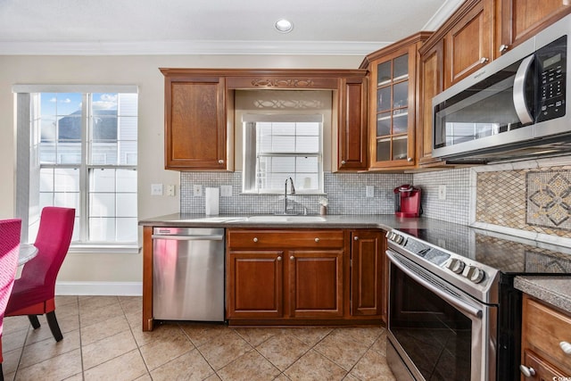 kitchen with sink, backsplash, ornamental molding, light tile patterned floors, and stainless steel appliances