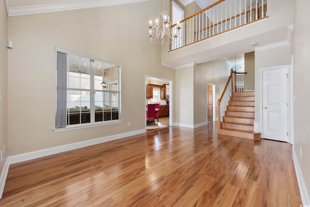 interior space with hardwood / wood-style flooring, crown molding, a high ceiling, and a notable chandelier