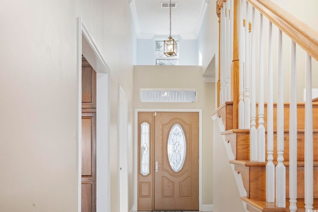 foyer entrance featuring crown molding, stairs, visible vents, and plenty of natural light