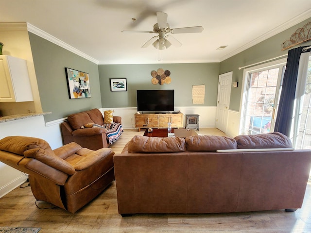 living room featuring visible vents, ornamental molding, light wood-style flooring, and a ceiling fan