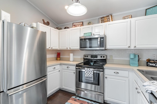 kitchen featuring crown molding, appliances with stainless steel finishes, white cabinets, dark hardwood / wood-style flooring, and decorative backsplash