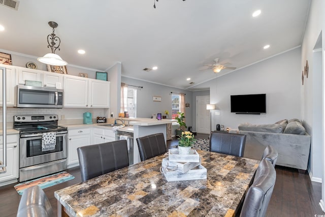 dining room featuring sink, crown molding, vaulted ceiling, dark hardwood / wood-style floors, and ceiling fan