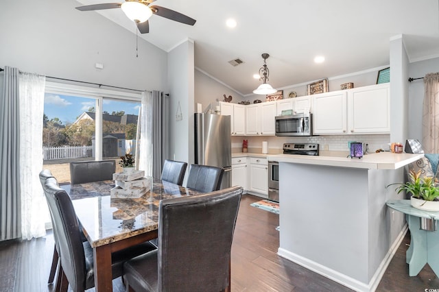 dining space with crown molding, ceiling fan, dark hardwood / wood-style floors, and vaulted ceiling