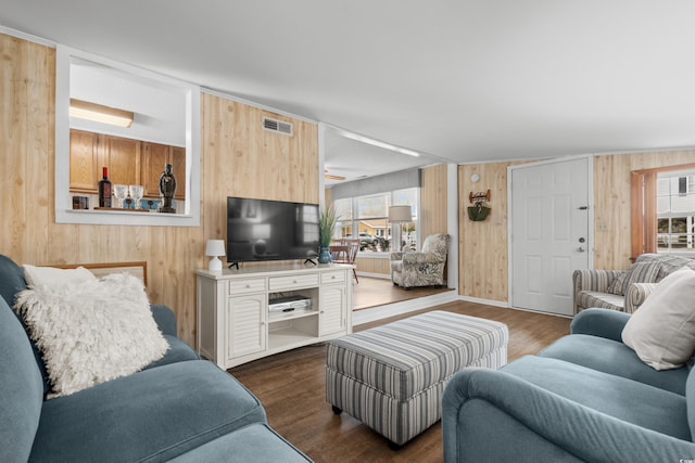 living area featuring a healthy amount of sunlight, wood walls, and visible vents