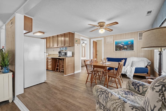 dining area featuring a textured ceiling, ceiling fan, wood finished floors, and visible vents