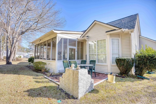 view of front of home featuring a sunroom, a patio area, and a front lawn