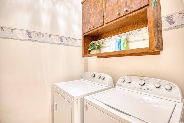 clothes washing area with separate washer and dryer and cabinets