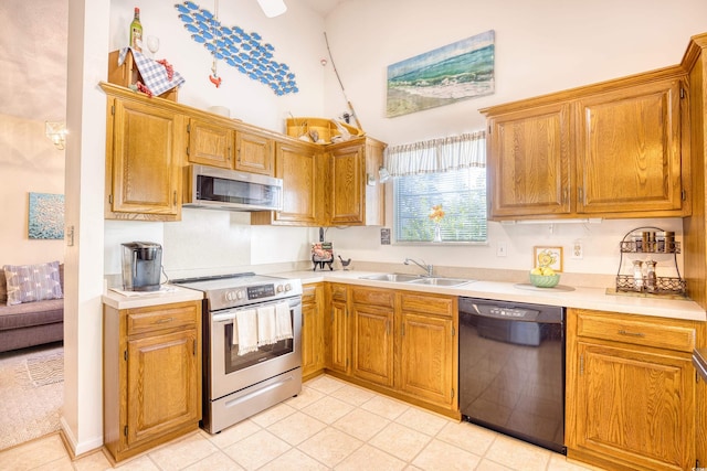 kitchen with sink, a towering ceiling, and stainless steel appliances