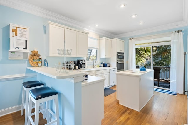 kitchen featuring white cabinetry, ornamental molding, double oven, and kitchen peninsula