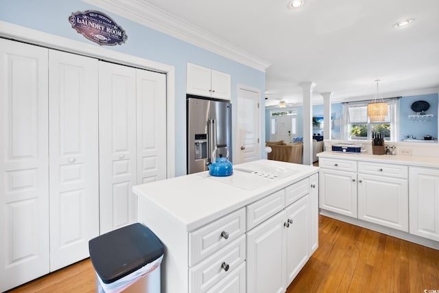 kitchen with high end refrigerator, hanging light fixtures, ornamental molding, a kitchen island, and white cabinets