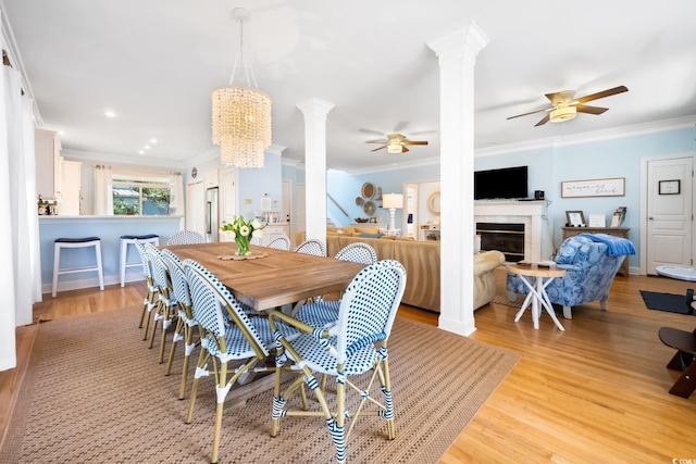 dining space featuring decorative columns, crown molding, ceiling fan, and light wood-type flooring