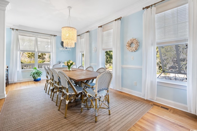 dining room with ornamental molding, light hardwood / wood-style floors, and a notable chandelier