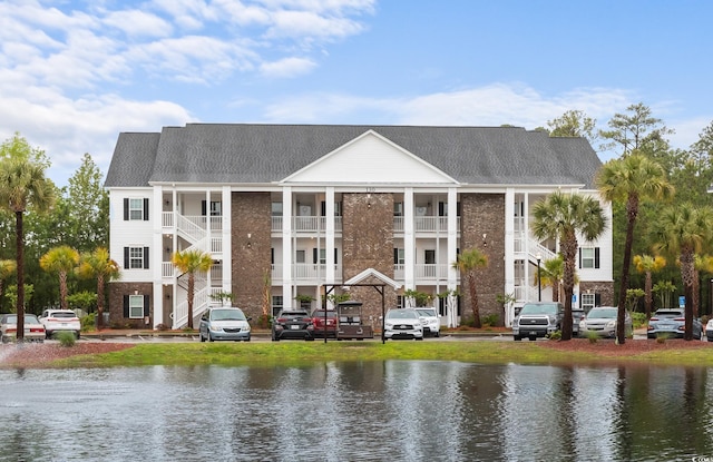 view of building exterior featuring a water view and uncovered parking