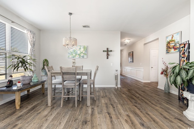 dining space featuring dark wood-type flooring and an inviting chandelier