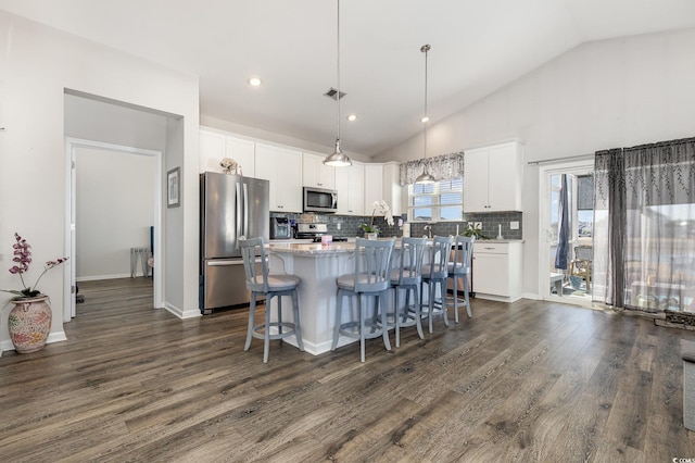 kitchen featuring appliances with stainless steel finishes, white cabinetry, dark hardwood / wood-style floors, a center island, and decorative light fixtures