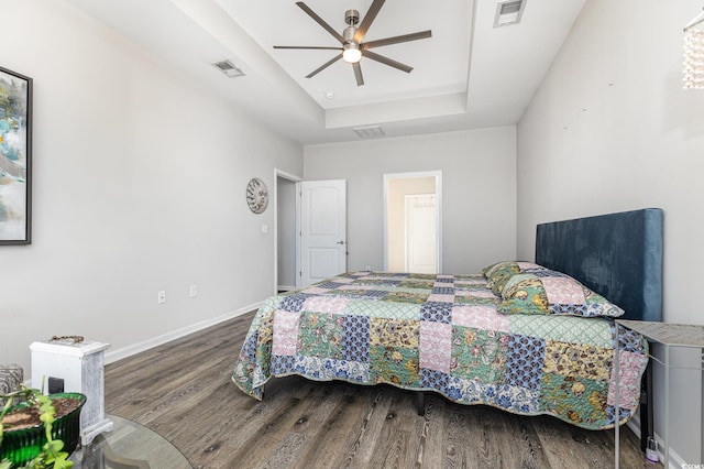 bedroom with hardwood / wood-style flooring, a raised ceiling, and ceiling fan