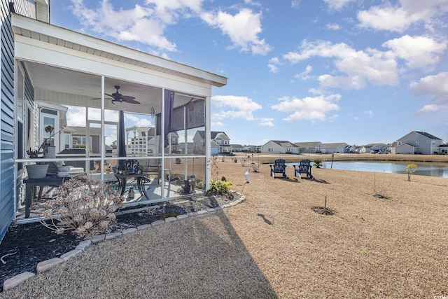 view of yard with a patio area, a sunroom, ceiling fan, and a water view