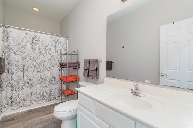 bathroom with toilet, recessed lighting, wood finished floors, and vanity