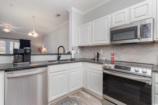 kitchen featuring white cabinets, ornamental molding, stainless steel appliances, light wood-style floors, and a sink