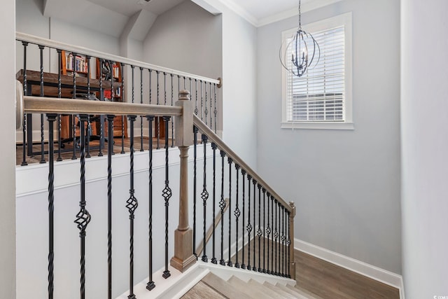 stairway with wood-type flooring, ornamental molding, and a chandelier