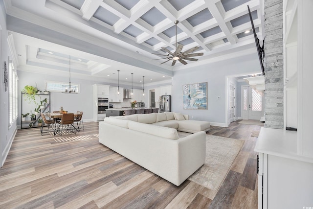 living room featuring a towering ceiling, beamed ceiling, coffered ceiling, light hardwood / wood-style floors, and crown molding