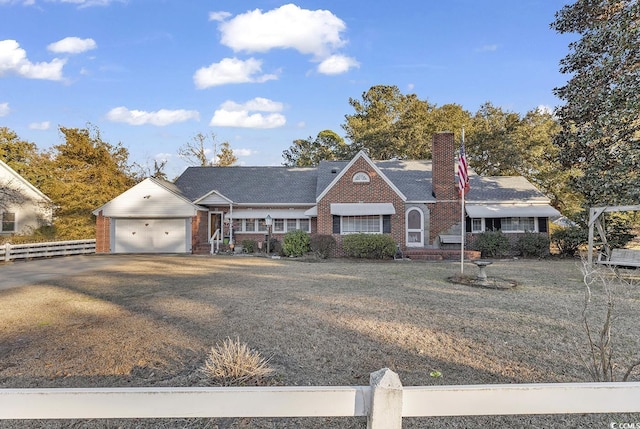 view of front facade with an attached garage, brick siding, fence, driveway, and a chimney