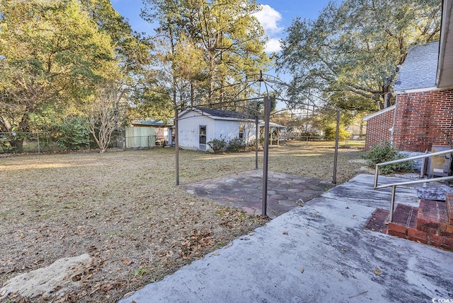 view of yard featuring fence, an outdoor structure, and a patio