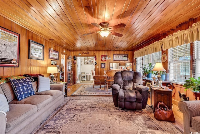 living area with wooden ceiling, wooden walls, a ceiling fan, and wood finished floors