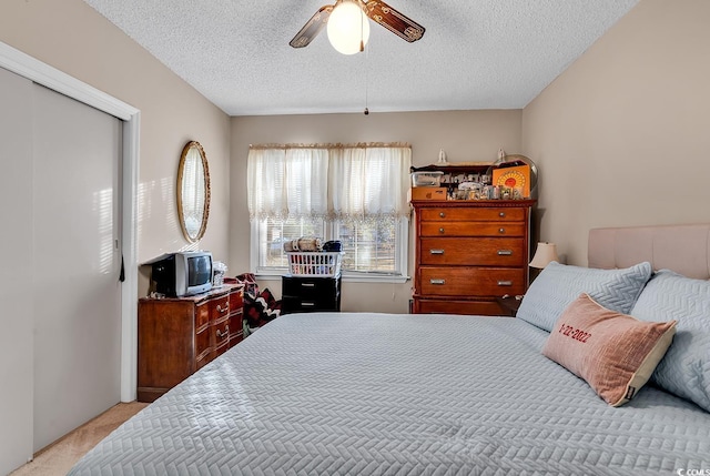 bedroom featuring light carpet, ceiling fan, and a textured ceiling