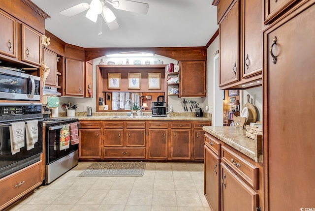 kitchen featuring a ceiling fan, appliances with stainless steel finishes, brown cabinets, under cabinet range hood, and a sink