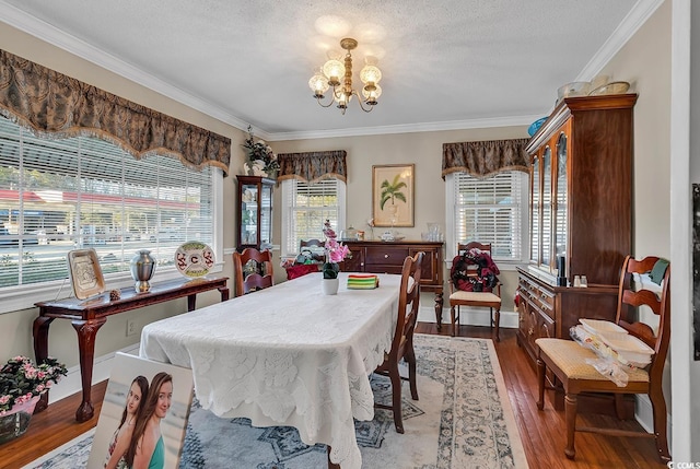 dining area with crown molding, a notable chandelier, a textured ceiling, and wood finished floors