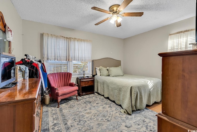 bedroom featuring light wood-type flooring, a ceiling fan, and a textured ceiling