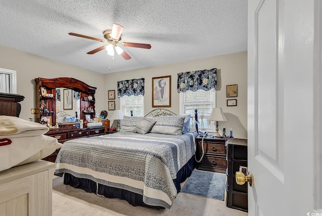 bedroom with a textured ceiling, a ceiling fan, and light colored carpet