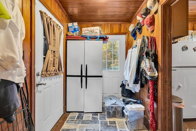 kitchen featuring wooden ceiling, wooden walls, and freestanding refrigerator