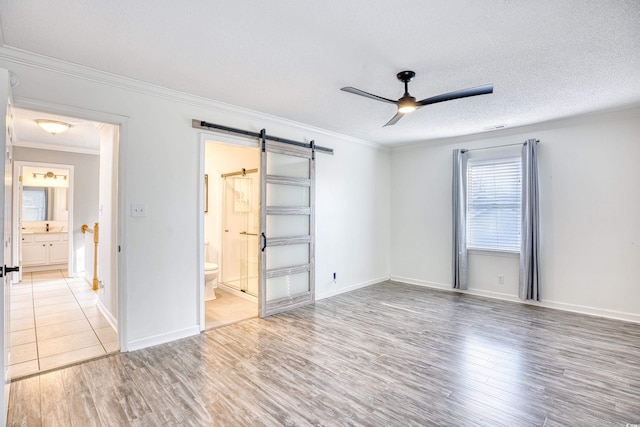 116 Great Lakes Rd, Pawleys Island, SC 29585 - unfurnished bedroom featuring crown molding, hardwood / wood-style flooring, a barn door, and a textured ceiling