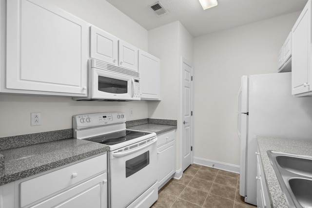 kitchen featuring sink, white appliances, white cabinets, and dark tile patterned flooring