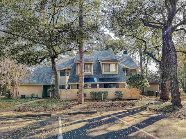 view of front of property featuring uncovered parking and a shingled roof