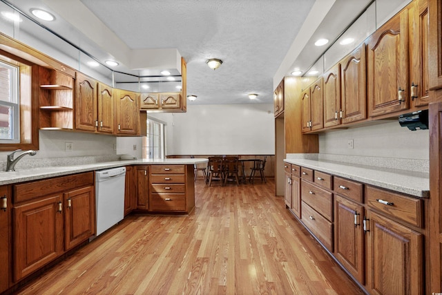 kitchen with sink, a textured ceiling, light wood-type flooring, kitchen peninsula, and dishwasher