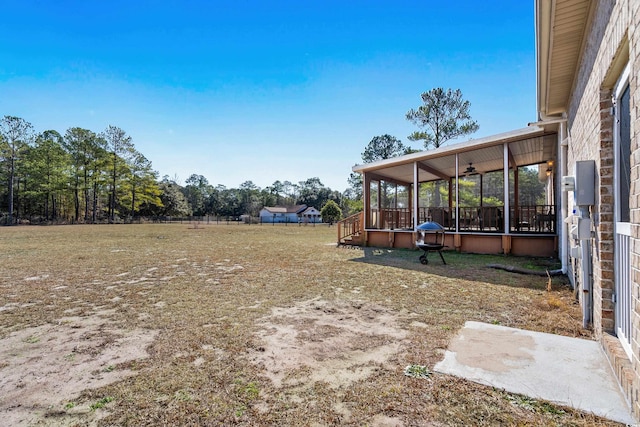 view of yard featuring a sunroom and ceiling fan