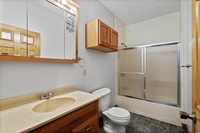 full bathroom featuring vanity, bath / shower combo with glass door, toilet, and a textured ceiling