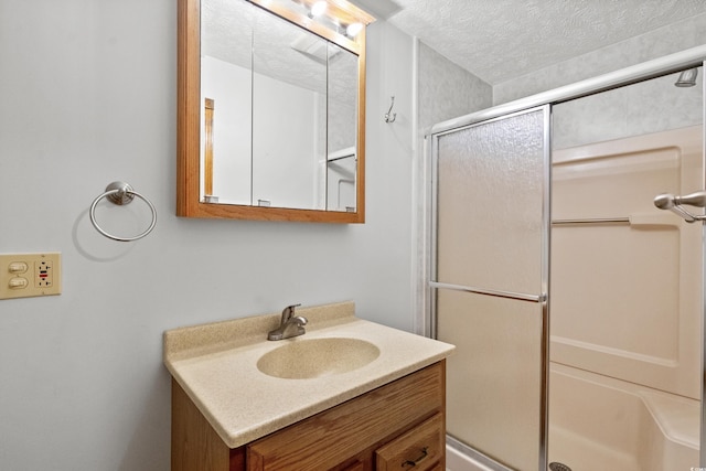 bathroom with vanity, a shower with shower door, and a textured ceiling