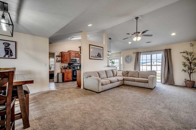 carpeted living room with ceiling fan, vaulted ceiling, and a textured ceiling